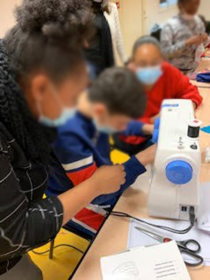 Des jeunes devant la machine à coudre